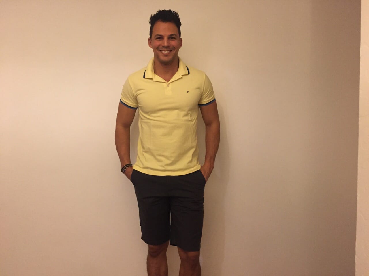 A man wearing a yellow polo and black shorts