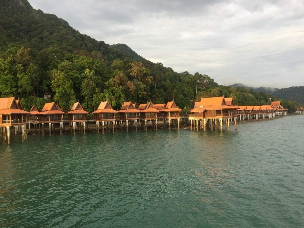 Bungalows sobre el agua en estilo malayo respaldados por montañas cubiertas de lujosa vegetación