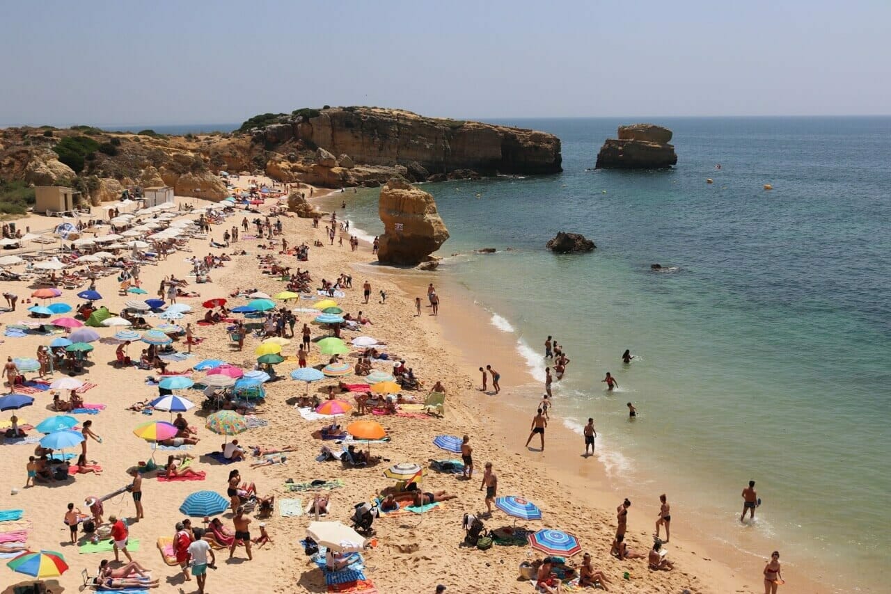 La gente en la arena y en agua de la Praia de São Rafael, Albufeira, Portugal