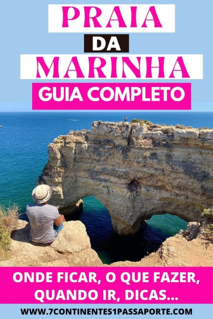 Um homem sentado na beira da Praia da Marinha perto de uma pedra em forma de coração