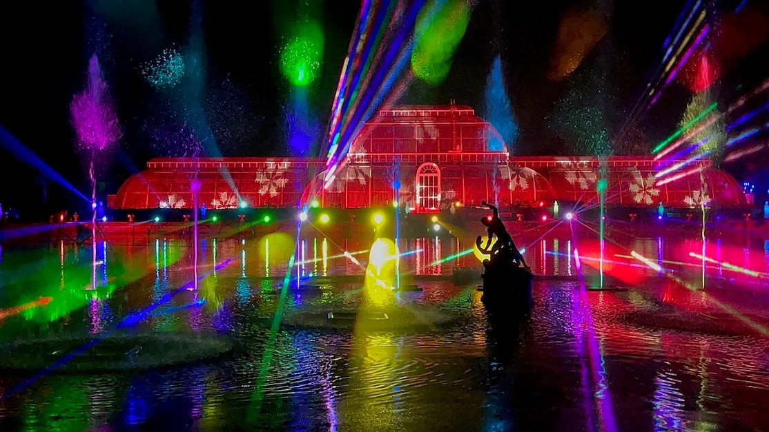 Uma projeção de iluminação impressionante através da casa de vidro histórica e lago adjacente durante Kew Gardens Luzes de Natal