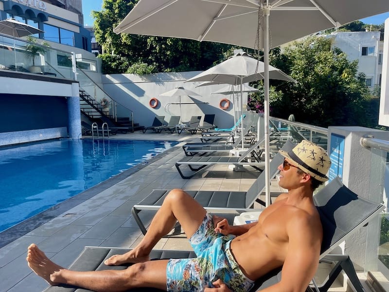 Péricles Rosa sentado em uma espreguiçadeira à beira da piscina no Semiramis City Hotel, Rhodes, Grécia