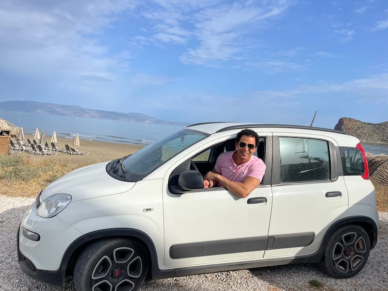 Pericles Rosa inside a Fiat Panda and a beach as a backdrop, Crete, Greece