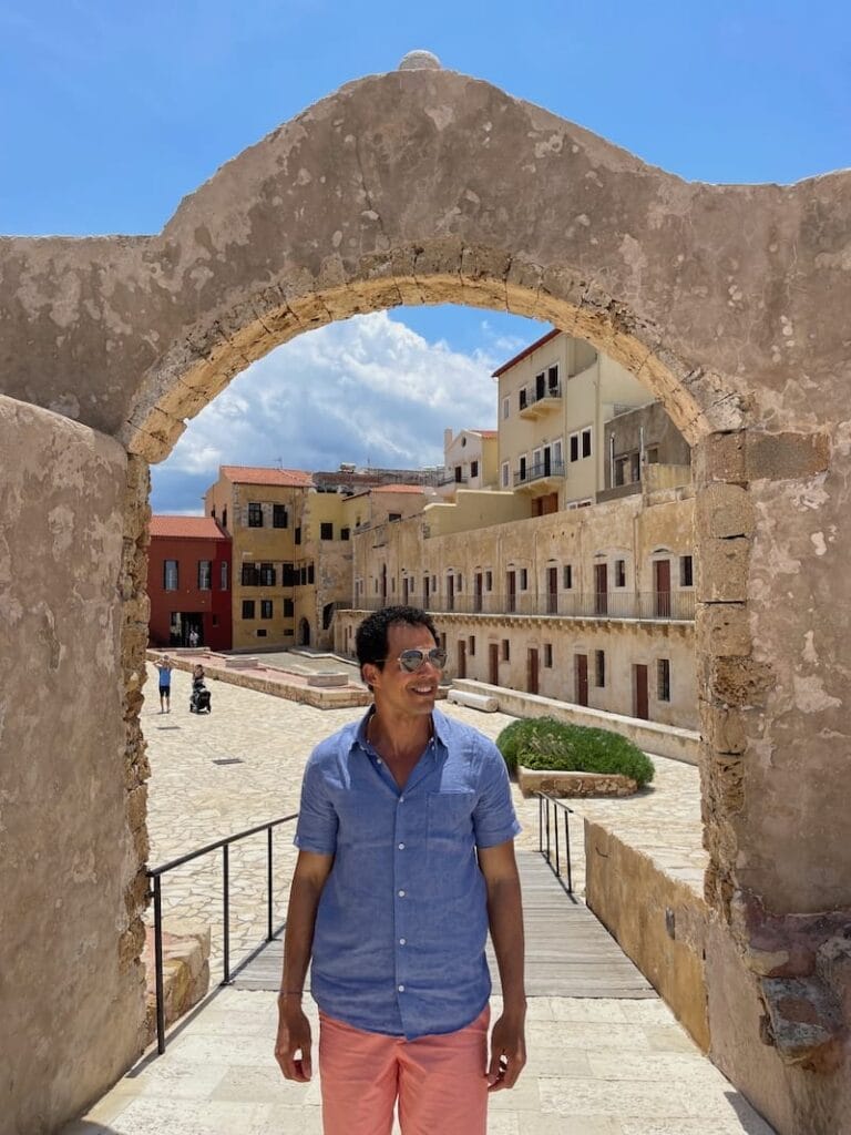 Péricles Rosa posando para uma foto em um arco na Fortaleza de Firkas, Chania, Creta, Grécia