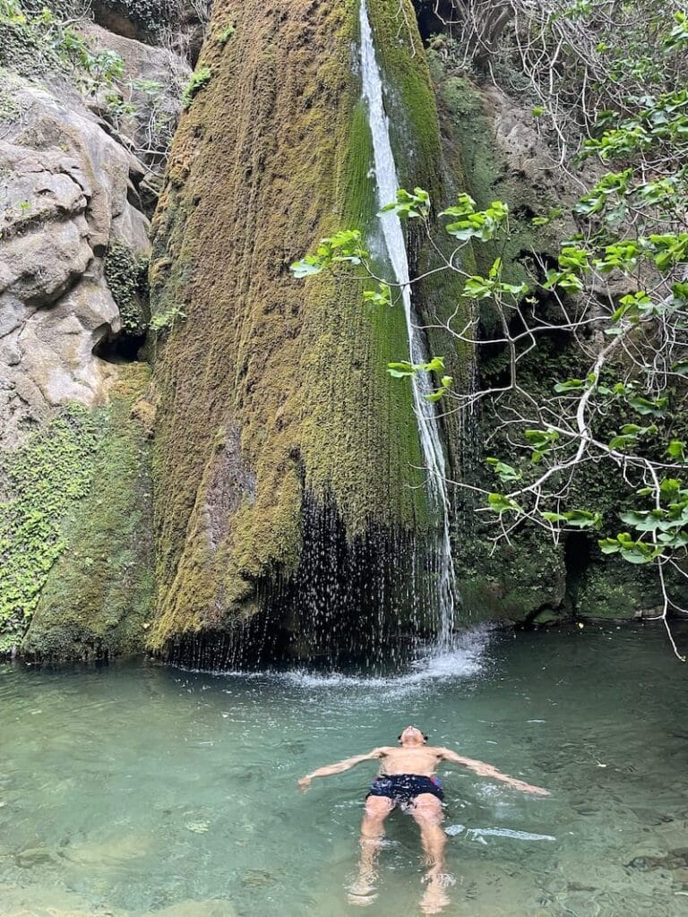 A man floating in fornt a waterfall at Ricthi Gorge, Crete, Greece