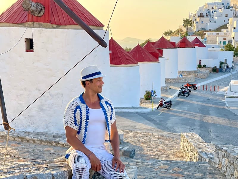 Pericles Rosa posing for a picture with the windmills of Astypalea, Greece